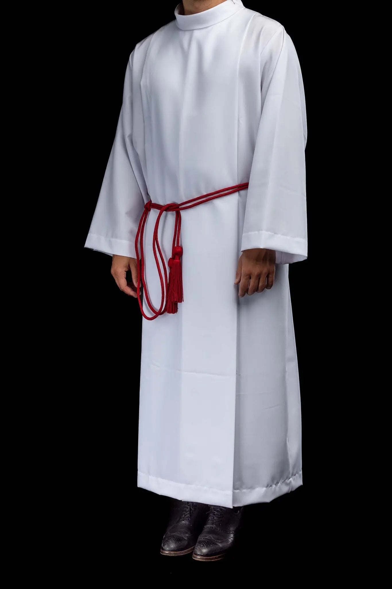 Red liturgical cincture with decorative tassels made from braided cord, tied around an alb.