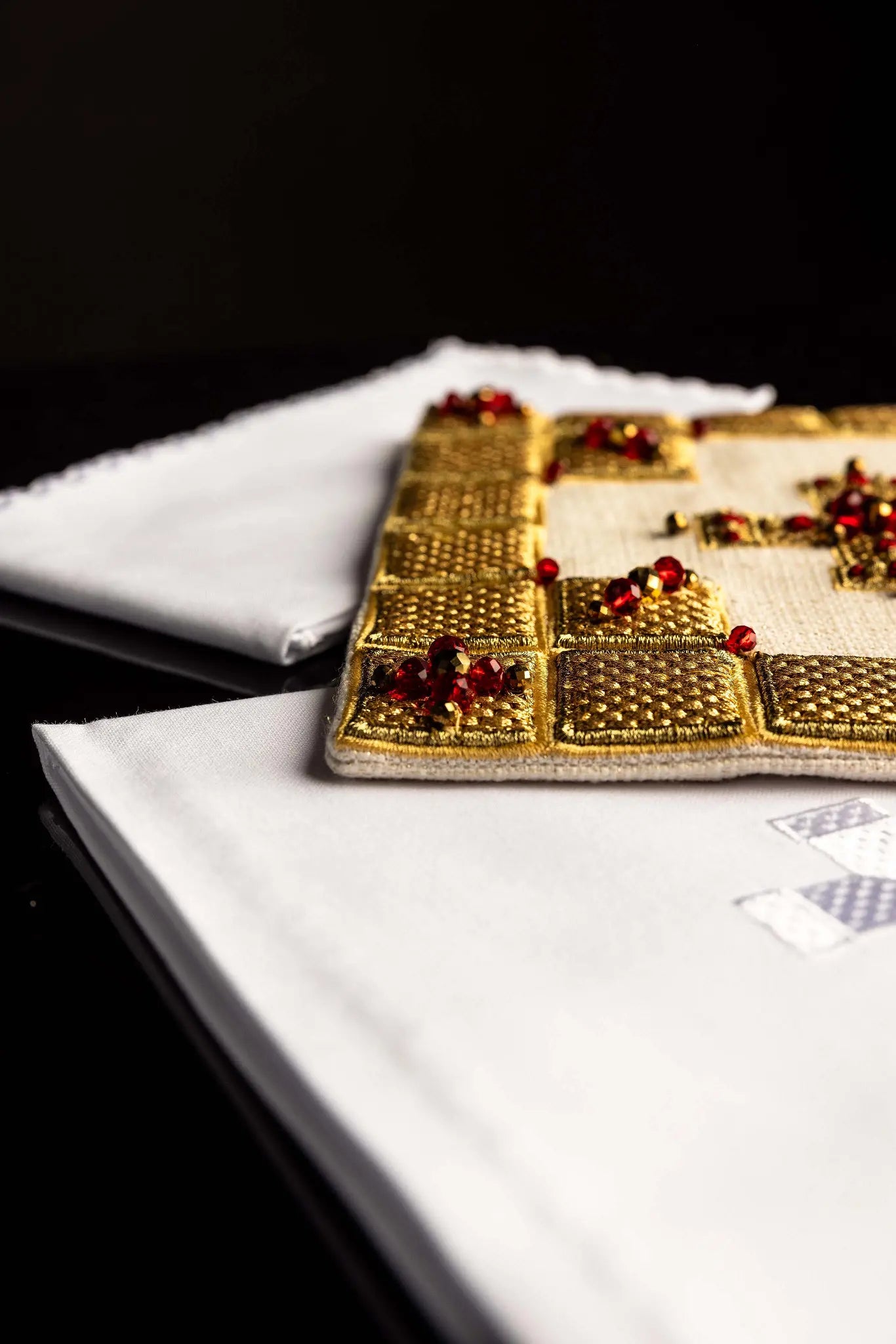 Ecru handmade chalice linen set with a pall featuring a dimensional gold cross, red hematite, and shimmering crystals, a corporal with a central cross, and a purificator and lavabo towel with embroidered crosses, all with scalloped edges.
