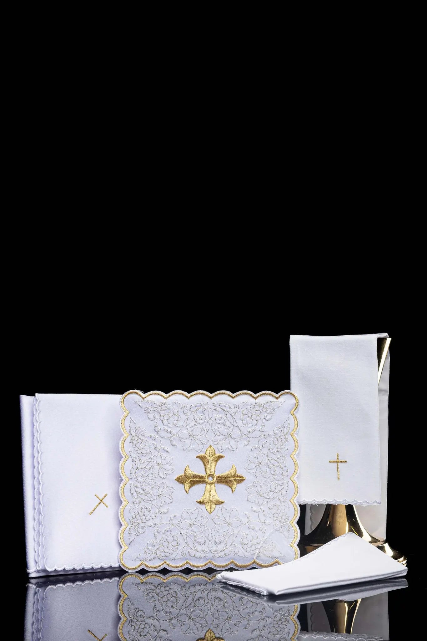 White chalice linen set with gold embroidered cross motif, including pall, corporal, purificator, and lavabo towel.
