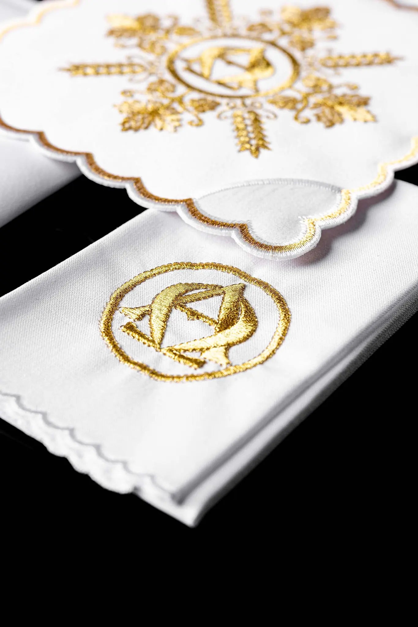 White chalice linen set with gold Alpha and Omega embroidery, including pall, corporal, purificator, and lavabo towel.