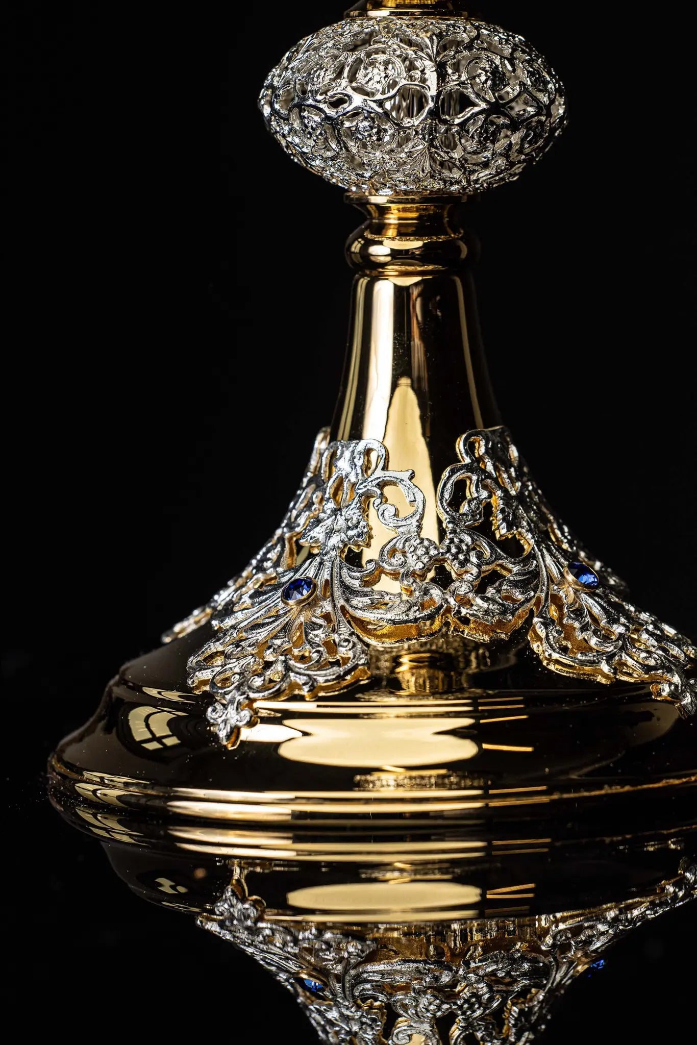 Handmade gold-plated liturgical chalice with silver-plated floral ornamentation and blue sapphire-like stones. The chalice features a decorated cup, nodus, and base.