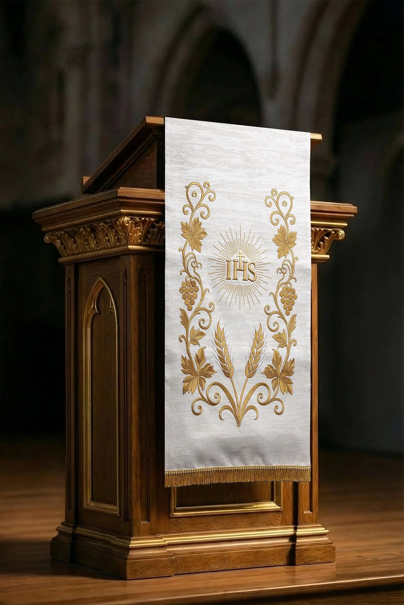 Ecru lectern cover with rich gold IHS monogram embroidery, radiant glory, wheat sheaves, and grapevines, finished with gold fringes.