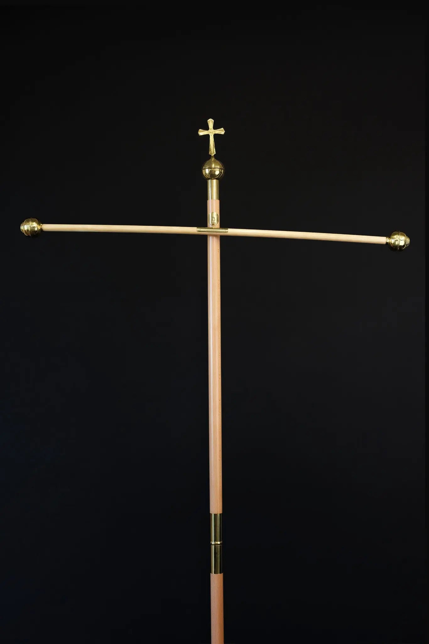 Light wood processional banner pole with decorative cross and gold metal accents