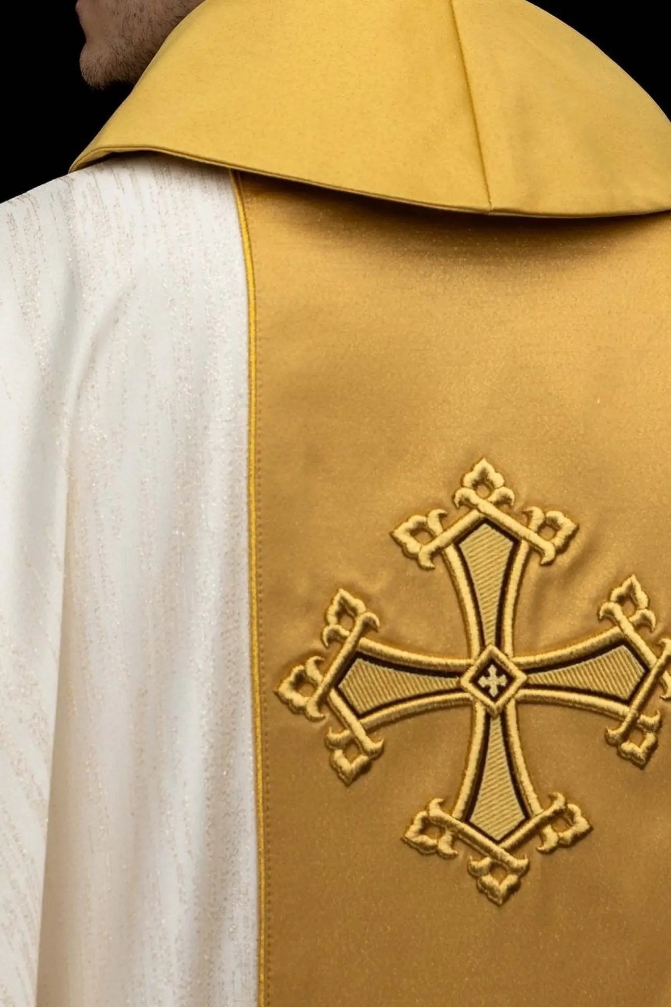 Ecru chasuble with embroidered cross motif and gold band on decorative fabric