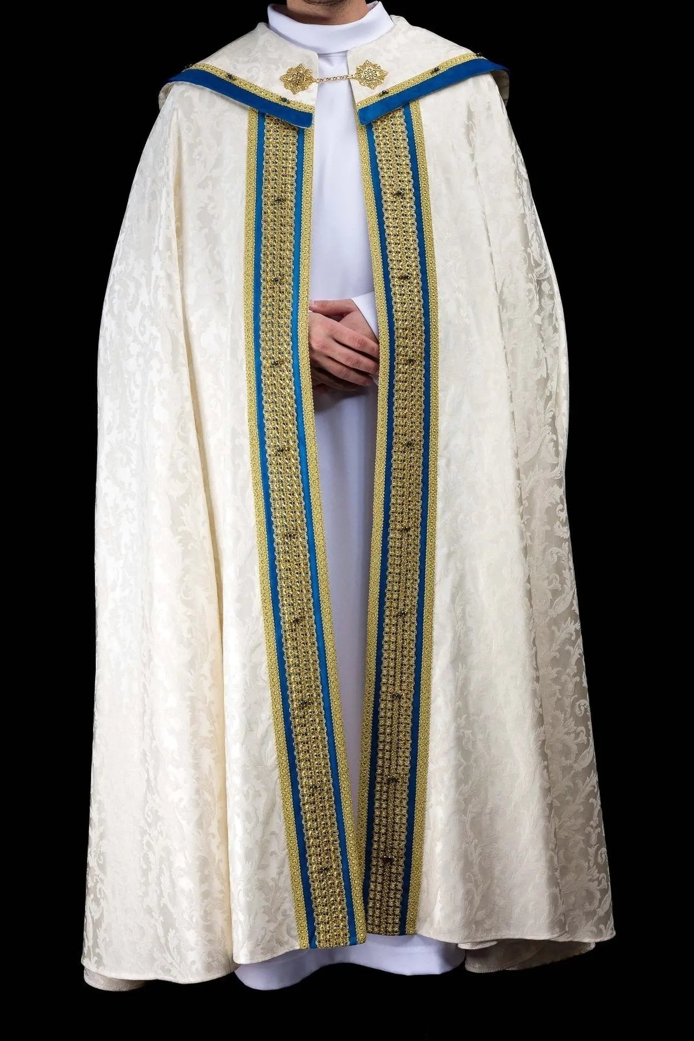 Ecru Marian cope with natural stones and blue velvet trim, part of the Handmade Collection, featuring an ornate metal clasp and gold tassel.