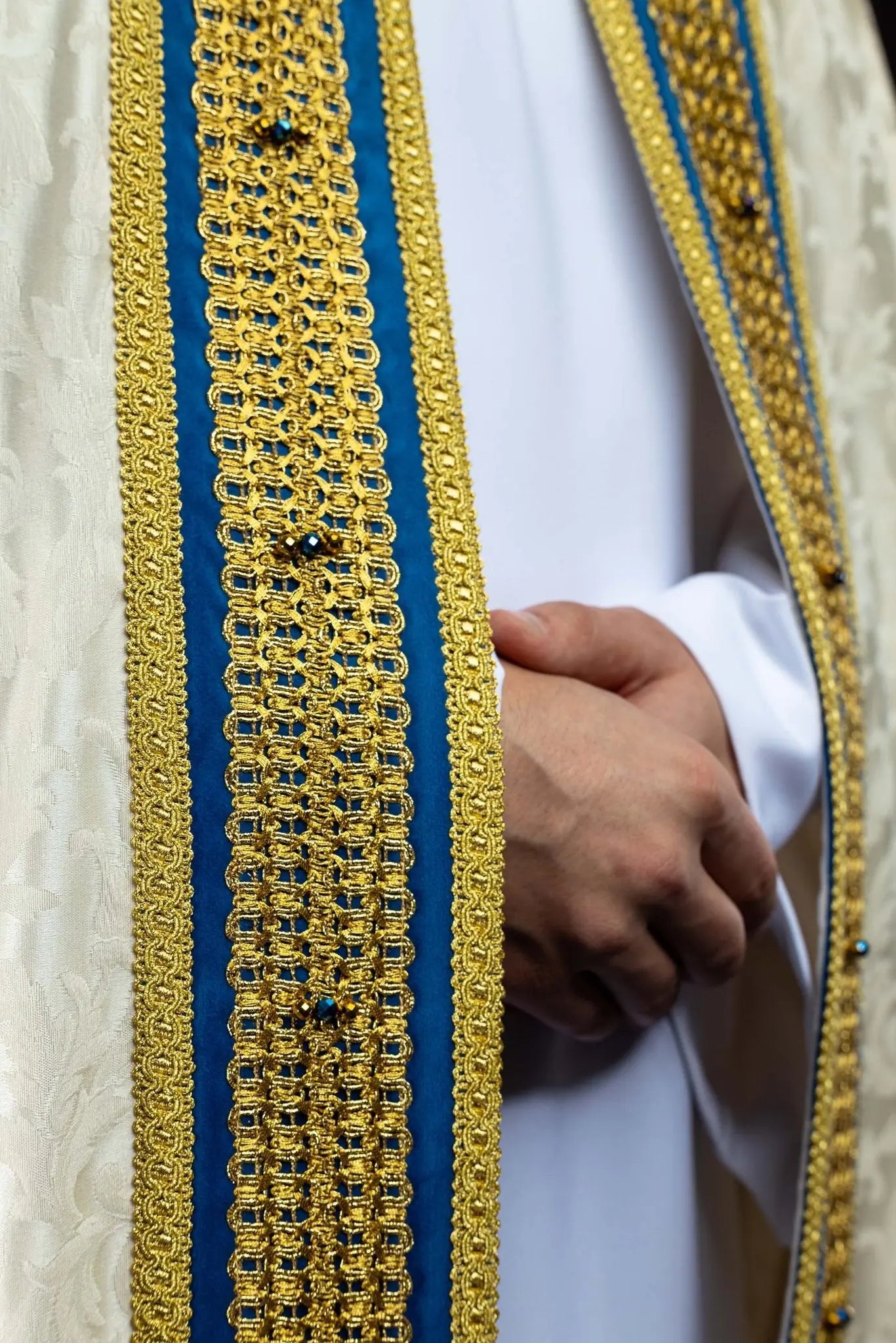 Ecru Marian cope with natural stones and blue velvet trim, part of the Handmade Collection, featuring an ornate metal clasp and gold tassel.