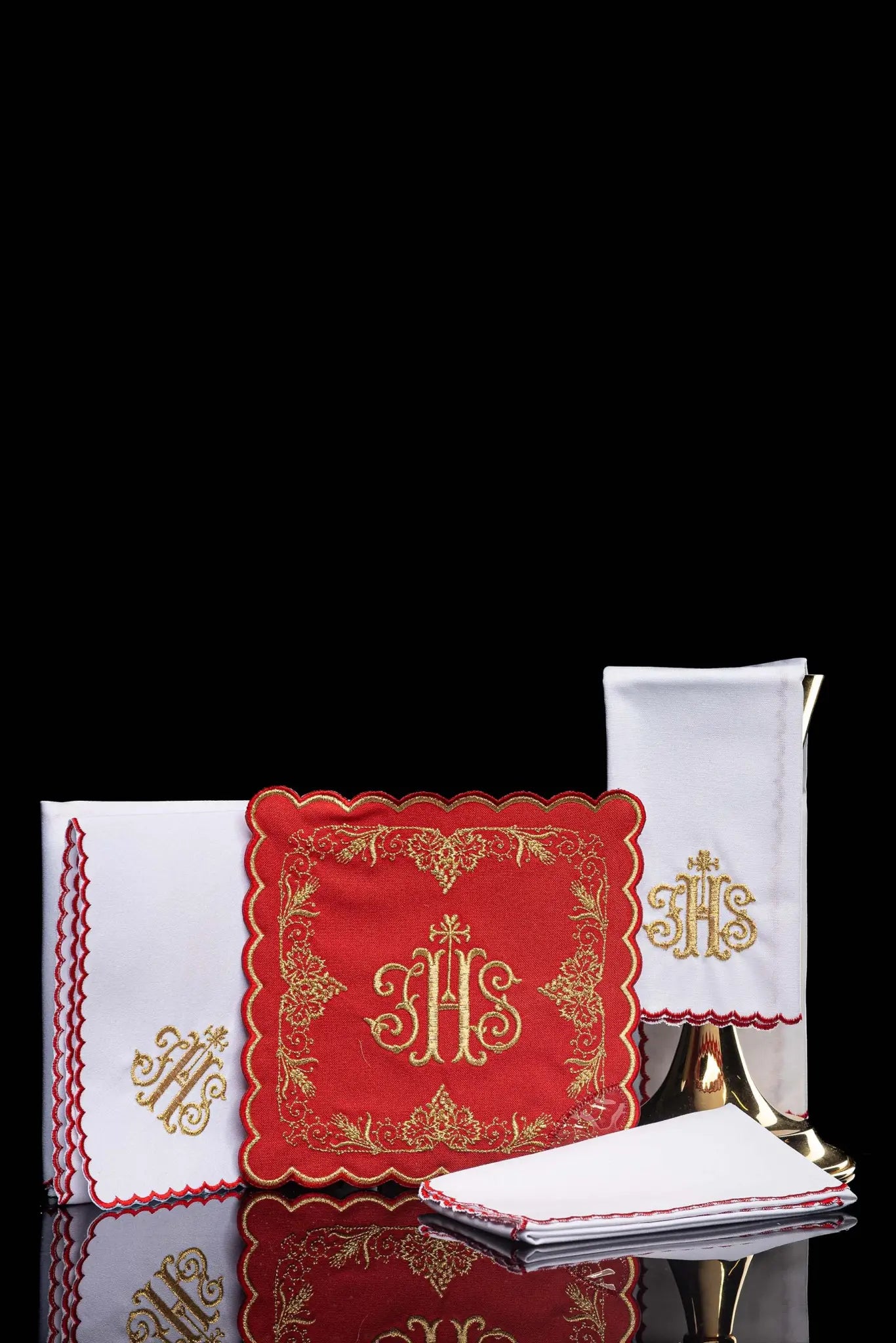 Red chalice linen set with gold IHS embroidery, including a pall, corporal, purificator, and lavabo towel.