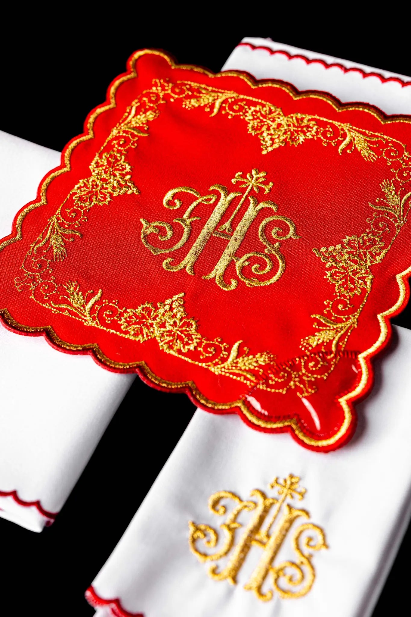 Red chalice linen set with gold IHS embroidery, including a pall, corporal, purificator, and lavabo towel.