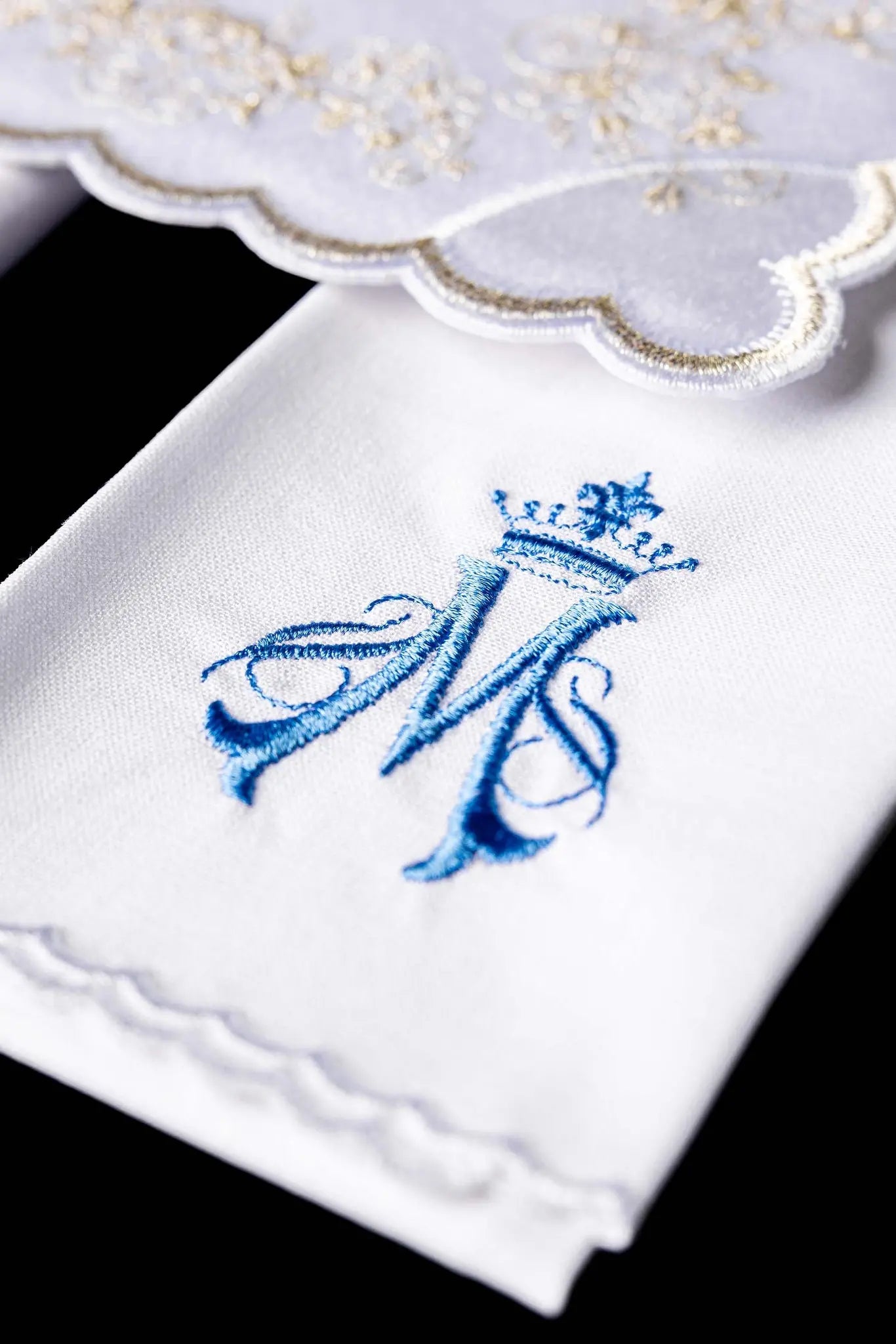 White chalice linen set with Marian monogram embroidery in blue and gold, including pall, corporal, purificator, and lavabo towel.