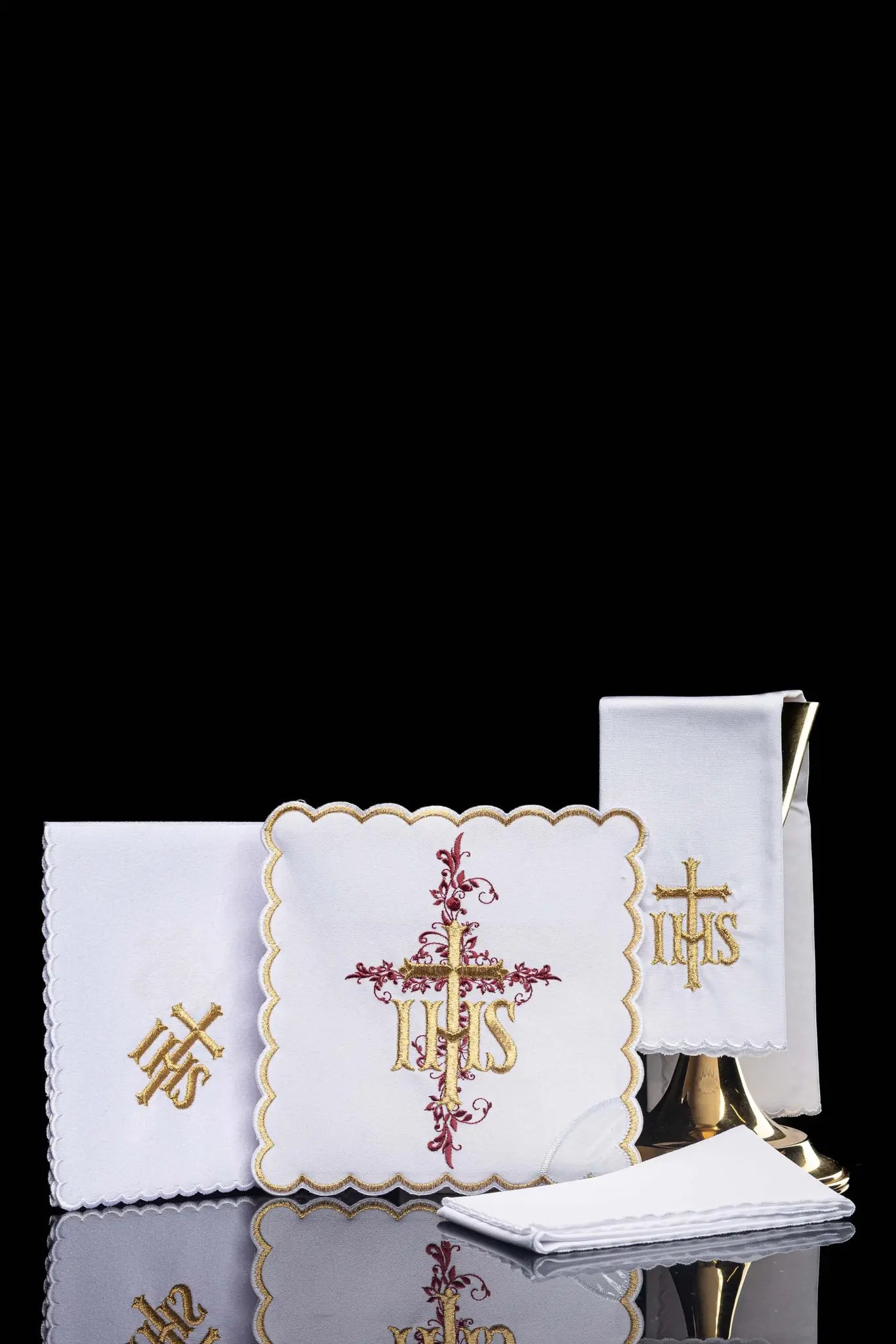 White chalice linen set with IHS embroidery, including pall, corporal, purificator, and lavabo towel.