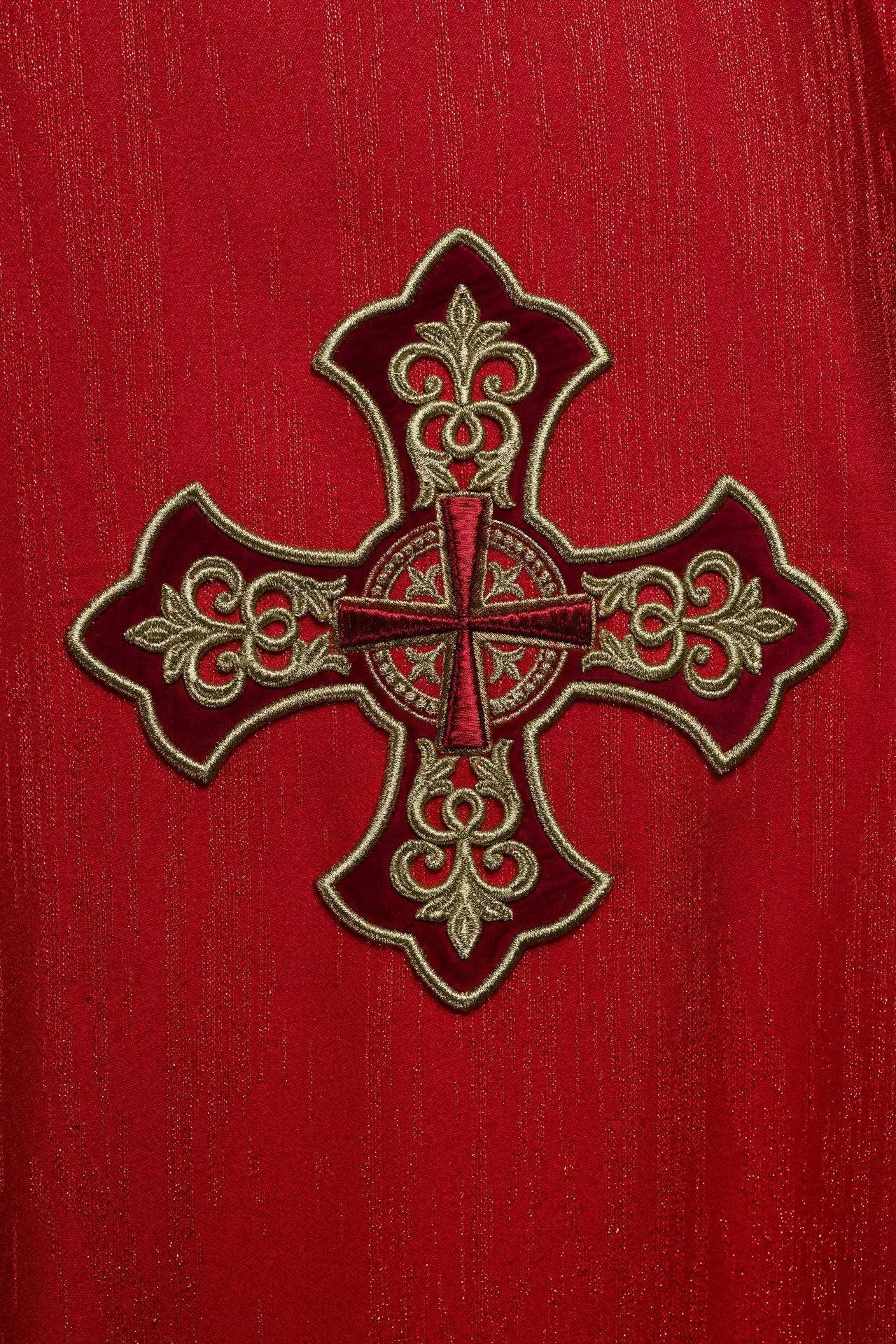 Red chasuble with embroidered cross motif on decorative fabric