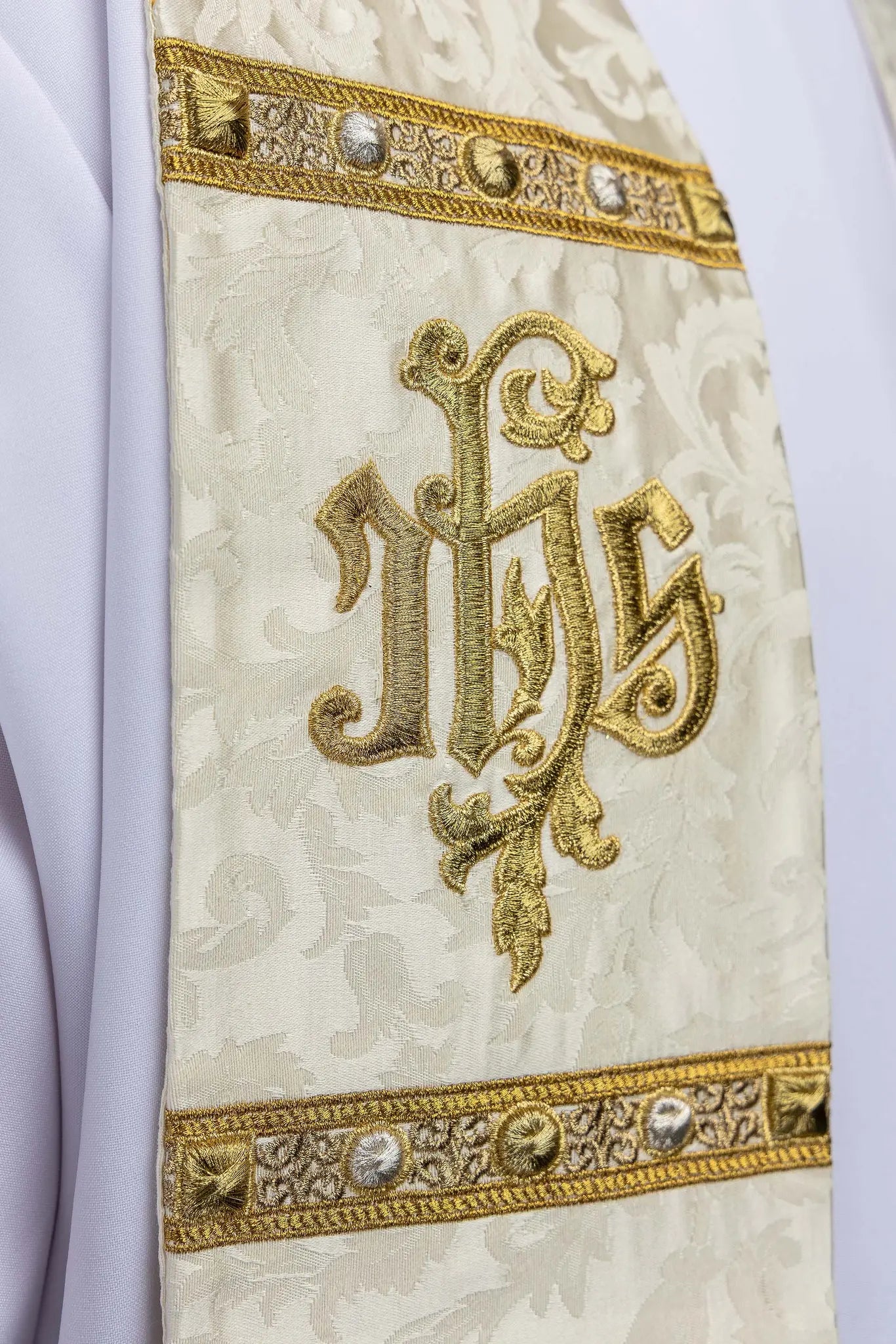 Ecru stole with Holy Family image on one side and IHS monogram on the other, featuring gold trim and tassels.