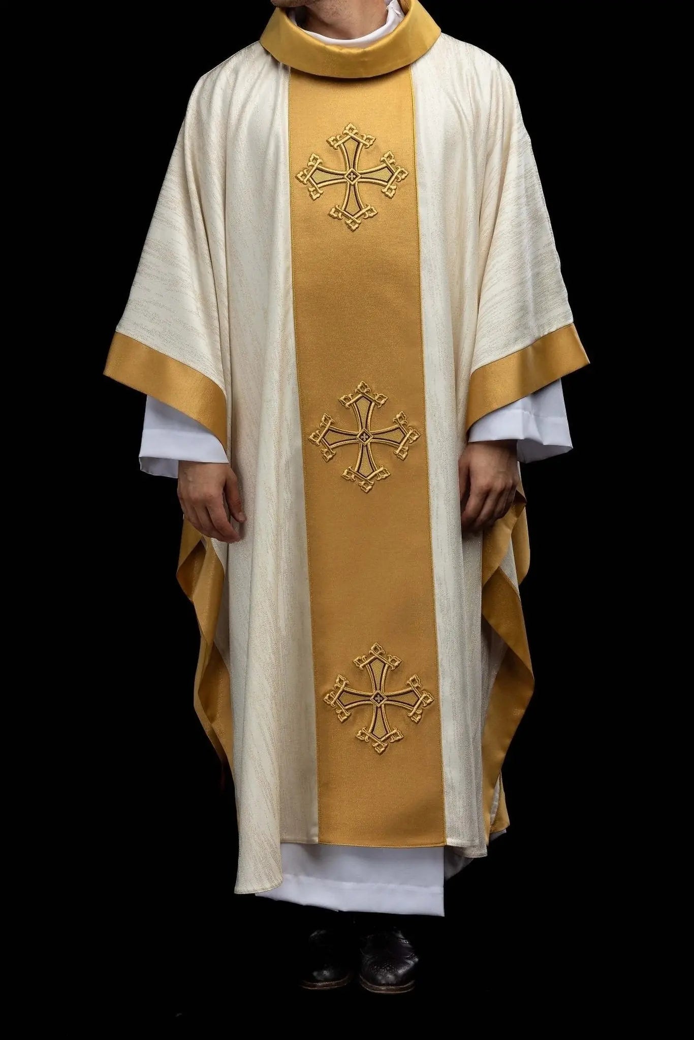 Ecru chasuble with embroidered cross motif and gold band on decorative fabric