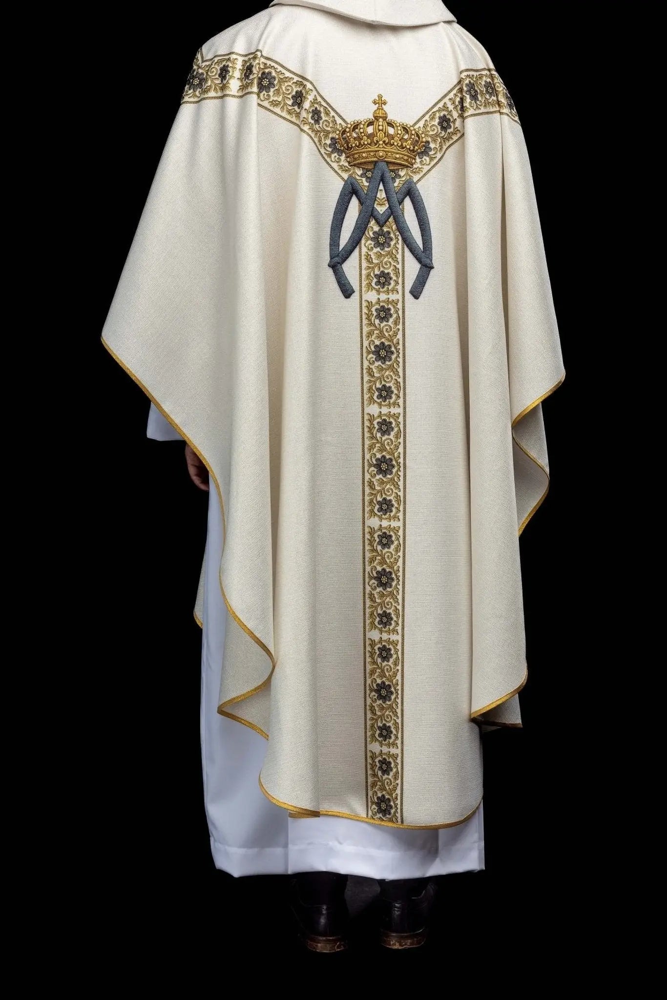 Ecru chasuble with printed image of Our Lady of Lourdes, featuring a blue sash and gold floral motifs, with a matching stole.