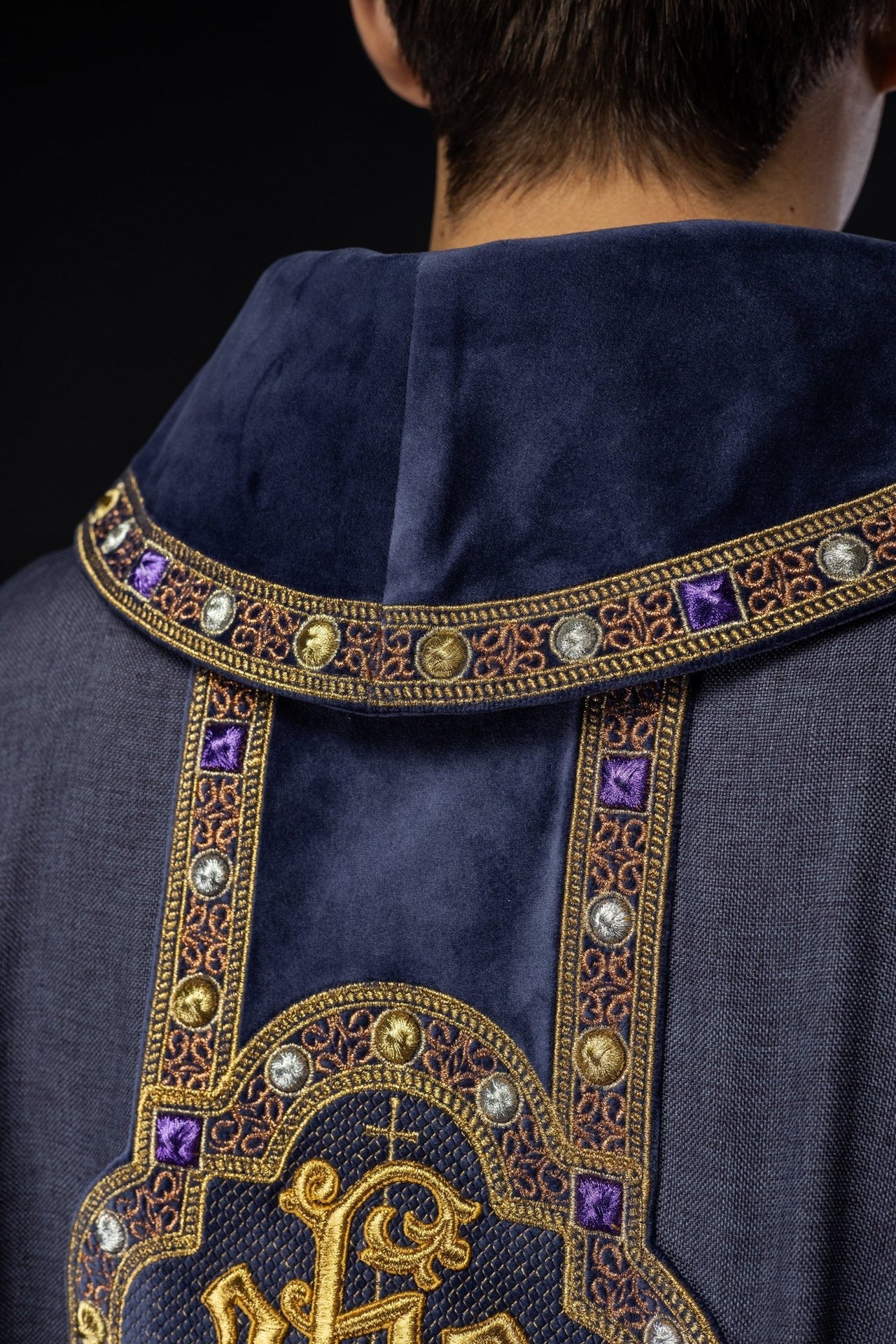 Ornat z bogato haftowanym pasem i lamówką wokół haftu IHS i kołnierza w kolorze fioletowym