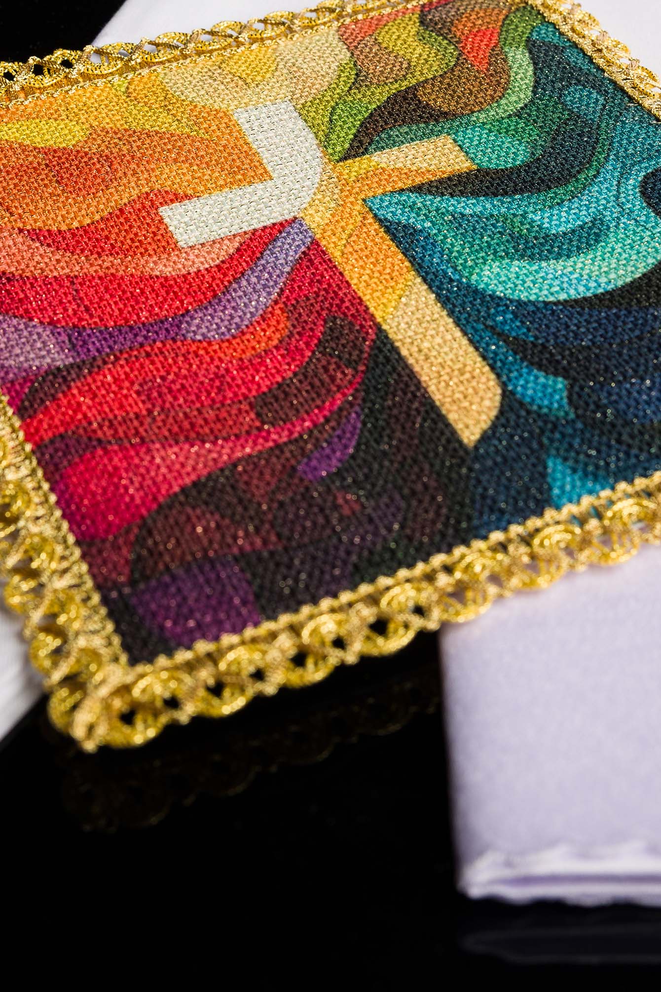 Detail of the pall showing stained-glass-style multicolour composition with a luminous cross
